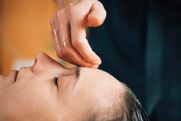 Woman enjoying Ayurvedic head and forehead massage therapy with essential oil in spa room